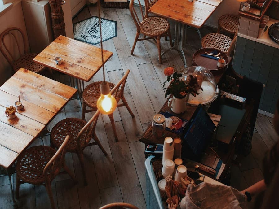 Kafe hangat dengan meja kayu dan lampu bohlam